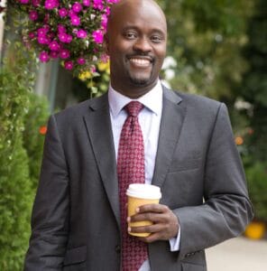 Adam Stanley in suit with coffee